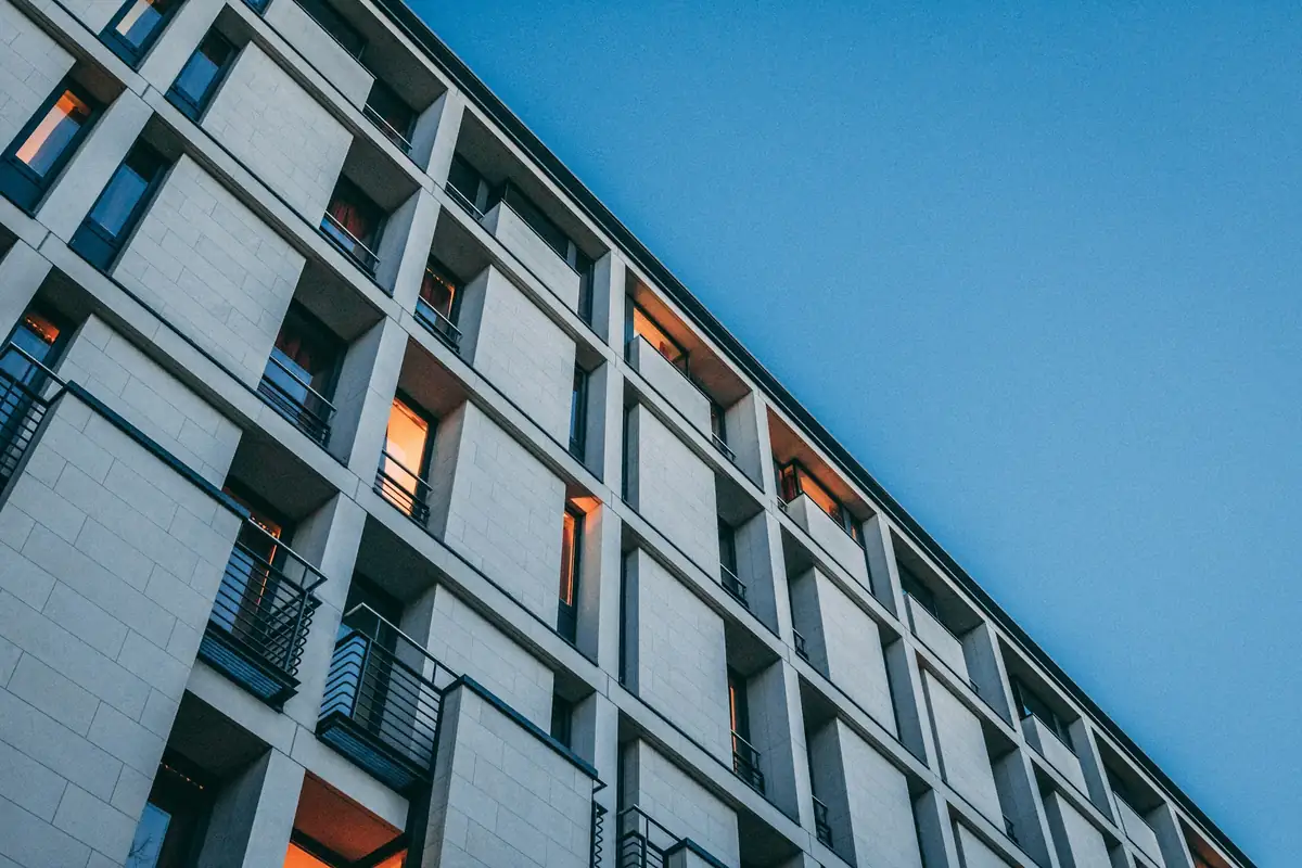 Façade d'immeuble en béton gris, balcons alignés en diagonale sur un ciel bleu